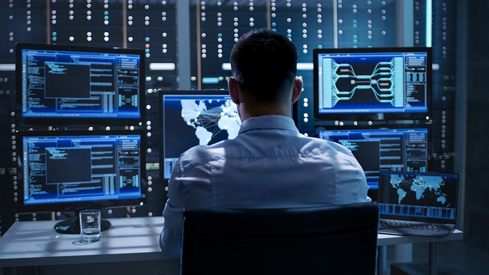 IT-Professional looks at data on multiple monitors