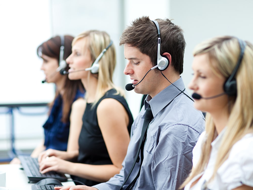 multiple professionals sit with headsets on taking calls