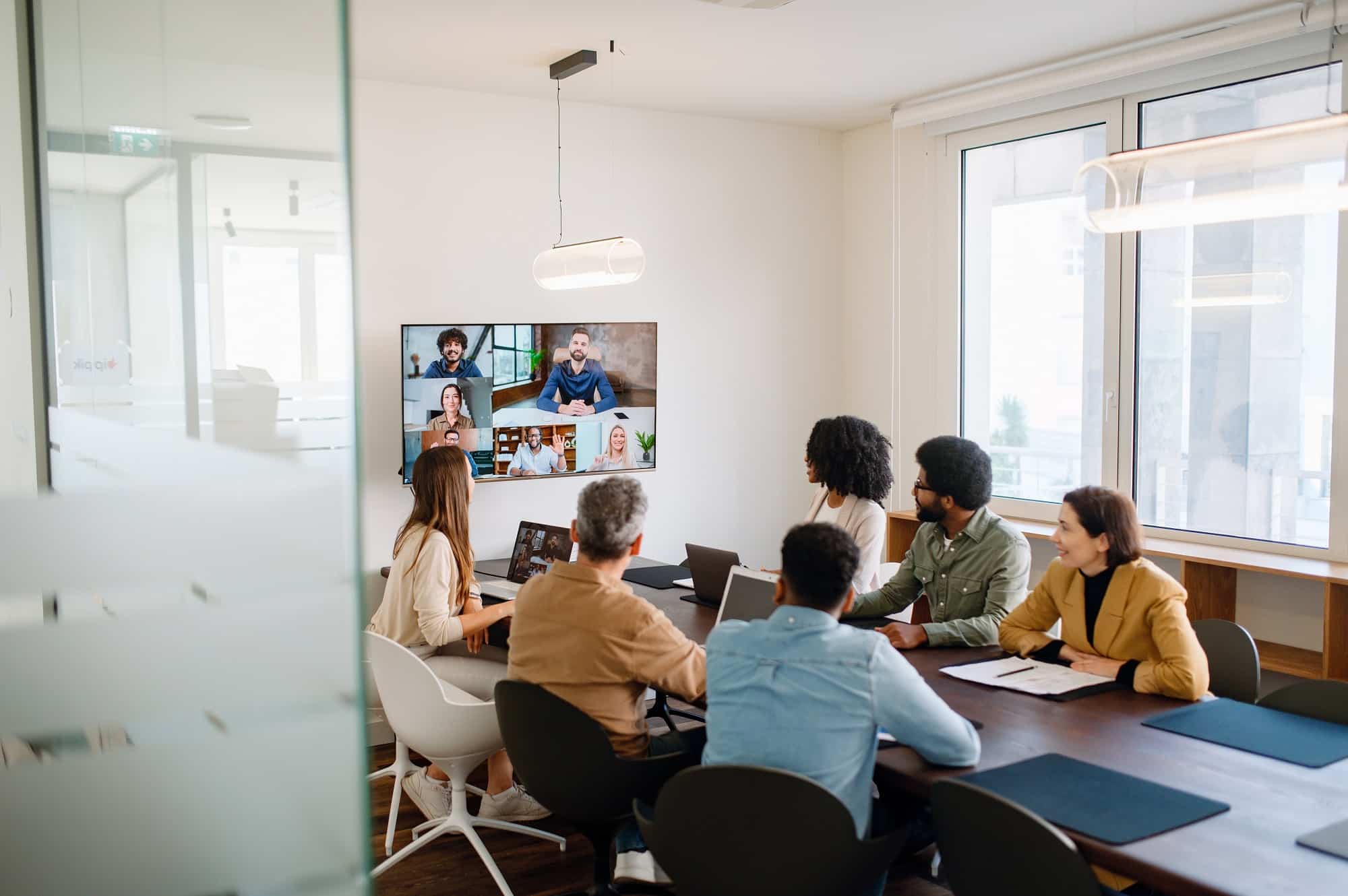 A team actively engages with remote colleagues via a large screen