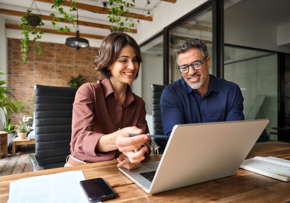 Business team of two executives working together using laptop in office