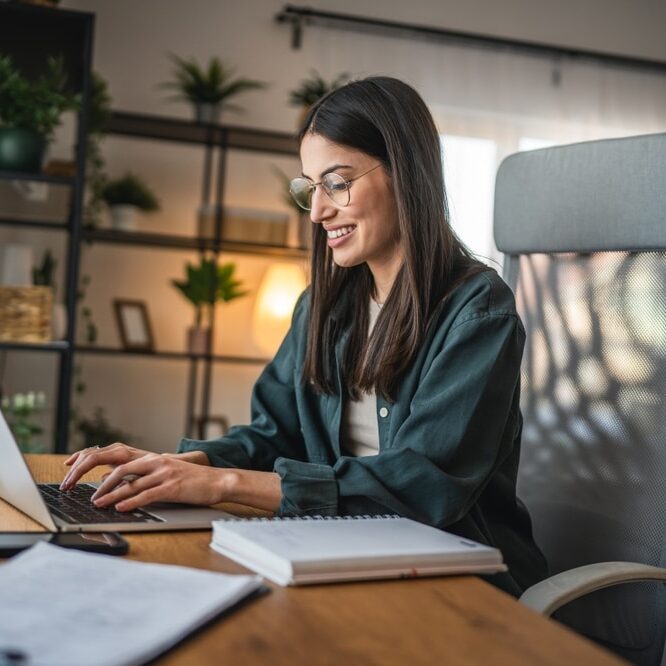 Adult woman work on laptop and use notebook from home office