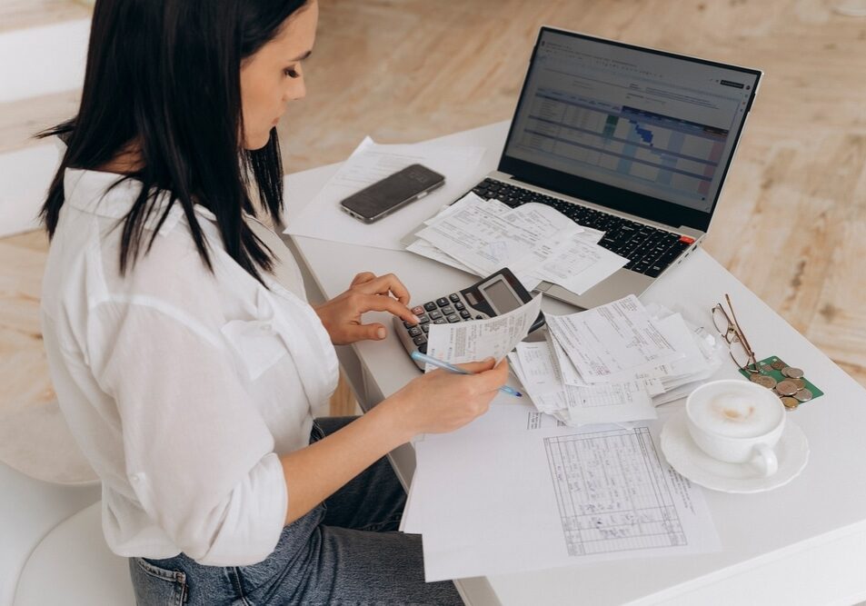 Side view of confident woman calculates utility expenses on laptop and calculator
