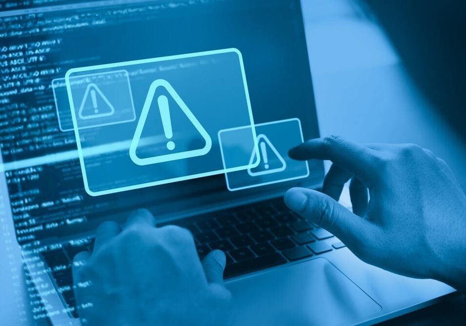 Man using computer with system hacked alert due to cyber attack on computer network Man using computer with system hacked alert due to cyber attack on computer network