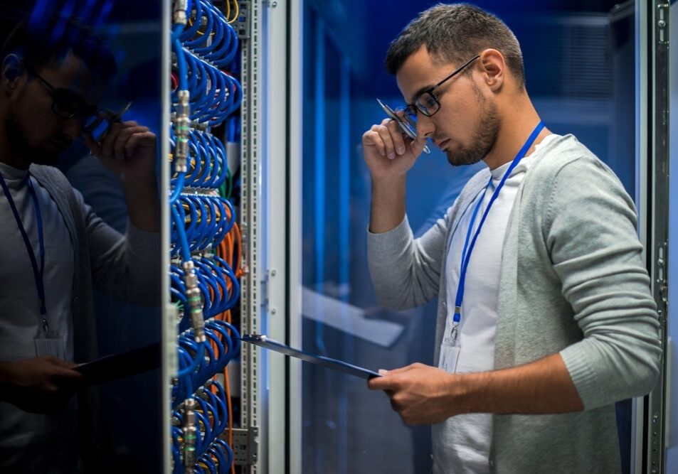 man standing by server cabinet while working with supercomputer in data center